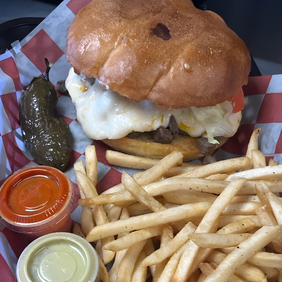 A Wall St. Cocina burger with fries, a roasted jalapeño, and two dipping sauces.