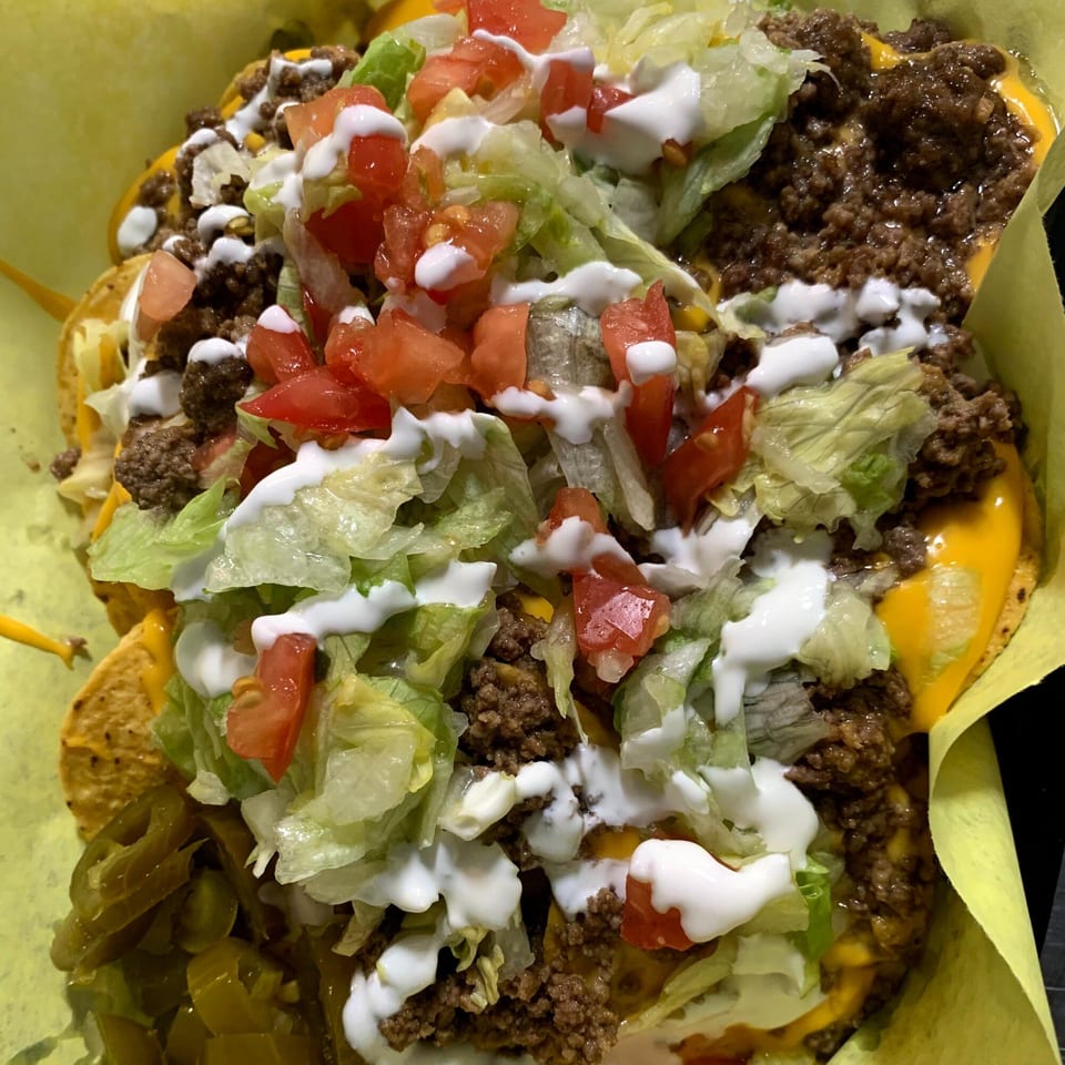 Wall St. Cocina's beef nachos with melted cheese, lettuce, tomatoes, sour cream, and jalapeños.