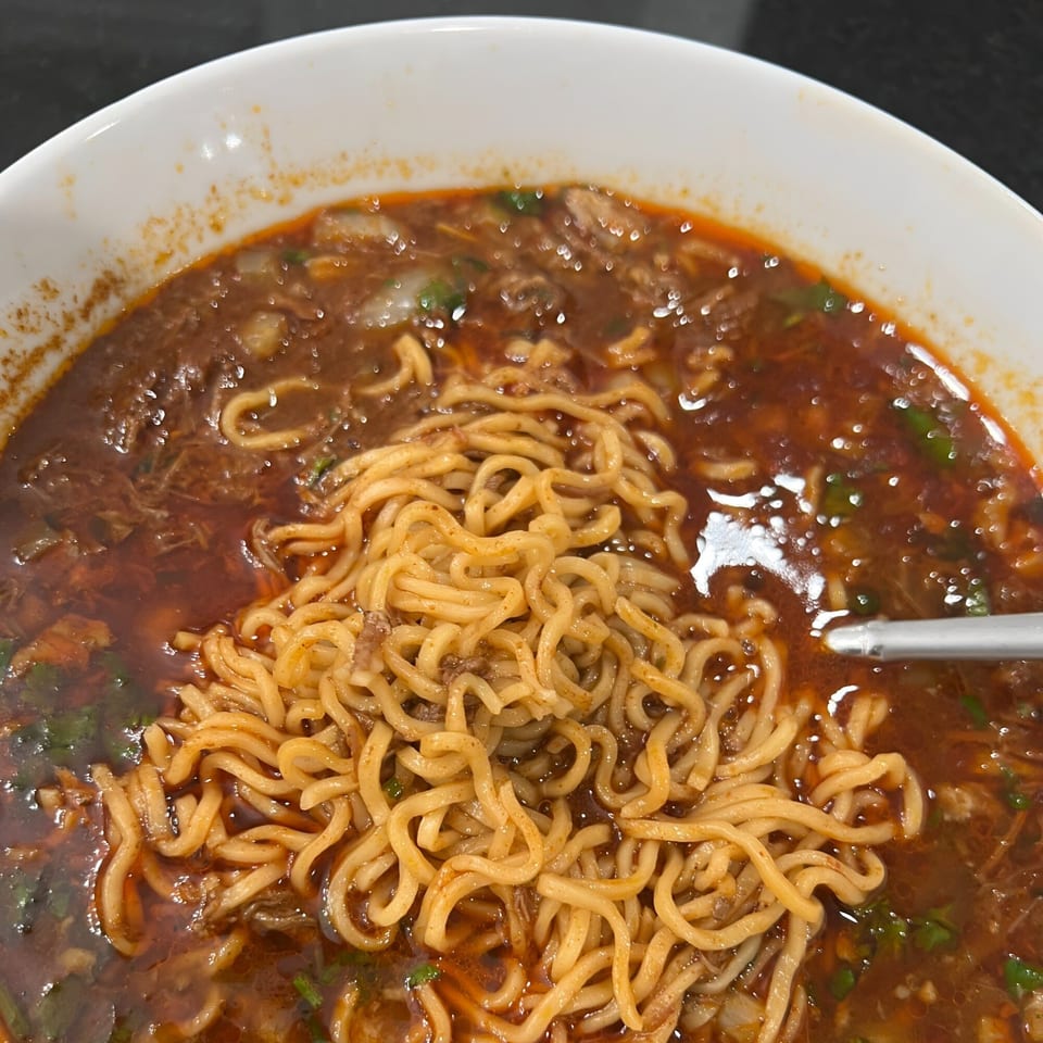 Close-up of a bowl of Wall St. Cocina's Mexican ramen with noodles and a rich broth.